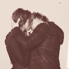 two people hugging each other in front of a cross