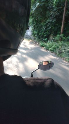 a person is riding down the road with a mirror on their head and there are trees in the background