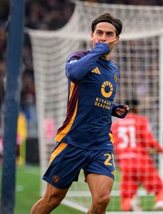 a soccer player is running on the field with his head in his hands and one hand up to his face