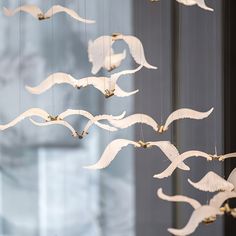 a group of white birds flying in the air with long tails and wings hanging from strings