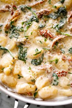 a pan filled with pasta and spinach covered in cheese