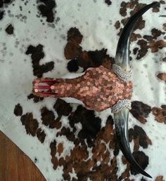 an animal skin and metal object on top of a cow print table cloth with other items around it