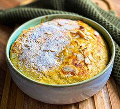 a baked dish with almonds and powdered sugar in a bowl on a wooden table