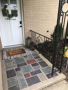 a front door with a welcome mat on the ground next to it and a black iron gate