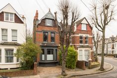 an empty street with some houses on the corner and trees in front of it,