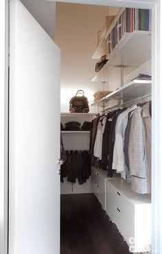 an open closet with clothes hanging on shelves