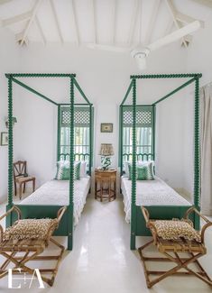 two beds in a room with white walls and green canopy beds on each side of them