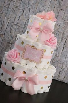 a three tiered cake decorated with pink and gold polka dots, bows and baby's name