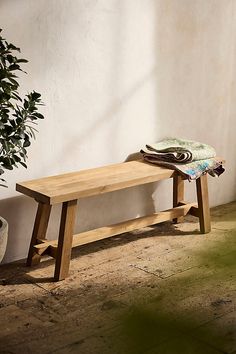 a wooden bench sitting next to a potted plant