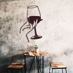 a table with two stools and a wine glass on the wall in front of it