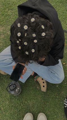 a person sitting on the ground with their head down and holding a cell phone in front of them