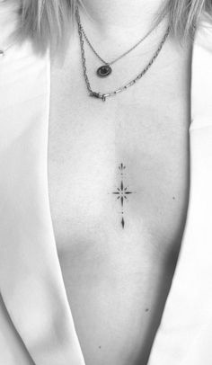 black and white photograph of a woman's chest with a cross tattoo on it