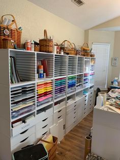 a room filled with lots of drawers and bins next to a wall mounted shelf