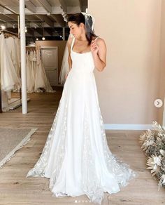 a woman standing in front of a wedding dress