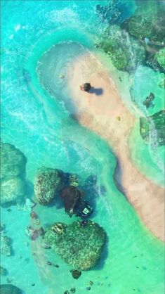 an aerial view of the ocean with rocks and algaes in blue water, as seen from above