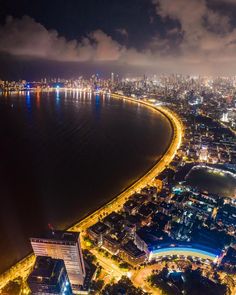 an aerial view of a city at night with the lights on and water in the foreground