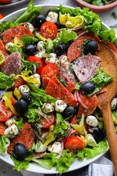 a salad with olives, tomatoes and mozzarella cheese in a white bowl