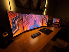 a desk with a keyboard, monitor and speakers on it in front of a large screen