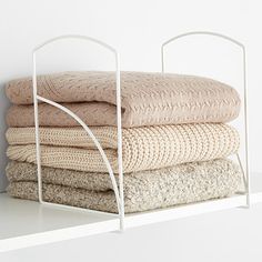 a stack of folded towels sitting on top of a white shelf