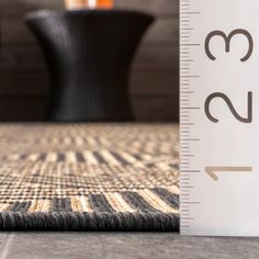 a tall ruler sitting on top of a carpet next to a table with a vase