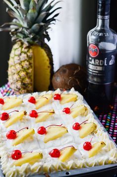 a pineapple and cherries decorated cake next to a bottle of boojute