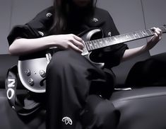 a person sitting on a couch with a guitar in their lap and one hand holding it