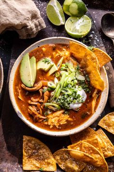 a bowl of chicken tortilla soup with tortillas and avocado