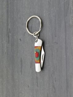 a bottle shaped keychain with a painting on it's front and back ends