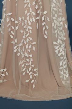 the back of a dress with white flowers and leaves on it's sheer fabric