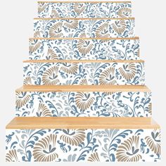 a set of stairs painted with blue and gold floral designs on white wallpaper, leading up to the second floor