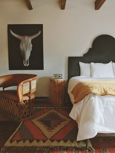 a bedroom with a bed, chair and cow skull on the wall above it's head