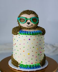 a birthday cake decorated with a slotty bear wearing sunglasses and sprinkles