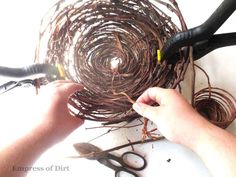 two hands are working on some wire and pliers to make a bird's nest