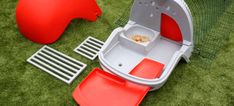 a red and white toy boat sitting on top of green grass next to a net