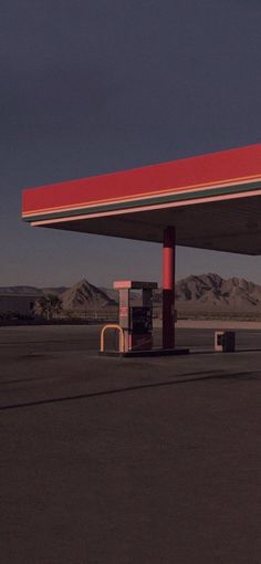 an empty gas station in the middle of nowhere, with mountains in the back ground