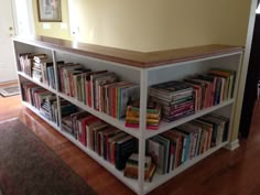 a bookshelf filled with lots of books on top of a hard wood floor