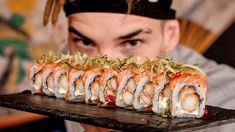 a man holding a tray with sushi on it