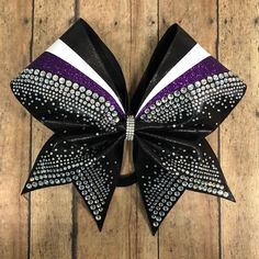 a black, white and purple cheer bow on wooden floor