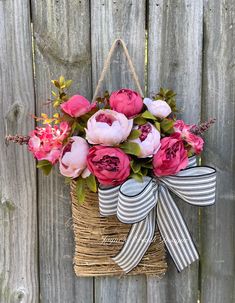 a basket filled with pink flowers on top of a wooden fence