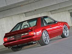 a red sports car parked in front of a concrete building with its door open and lights on