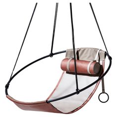 a pink and white swing chair hanging from a black metal frame with two leather straps