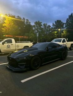 two cars parked in a parking lot next to each other on a cloudy day with the sun behind them