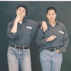 two people standing next to each other in front of a black background wearing jeans and hats