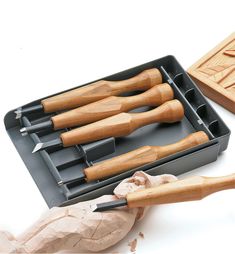 an assortment of wooden carving tools in a tray