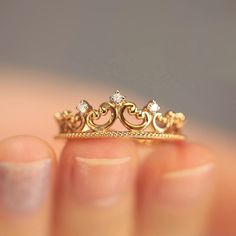 a close up of a person's hand holding a gold ring with diamonds on it