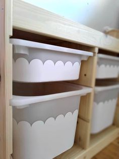 three white plastic containers sitting on top of a wooden shelf