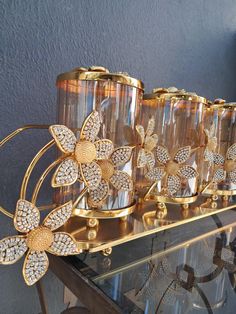 several gold colored vases with flowers are on a glass shelf