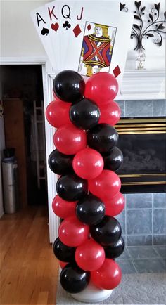 black, red and white balloons in front of a fireplace with playing cards on it