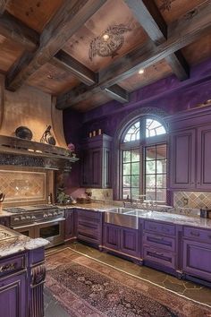 a large kitchen with purple cabinets and marble counter tops, along with an area rug on the floor