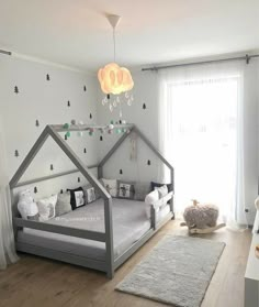 a child's bedroom decorated in white and grey with a tent shaped bed, rugs and curtains